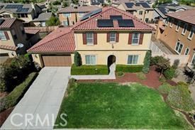 view of front of home featuring an attached garage, solar panels, a tile roof, concrete driveway, and a residential view