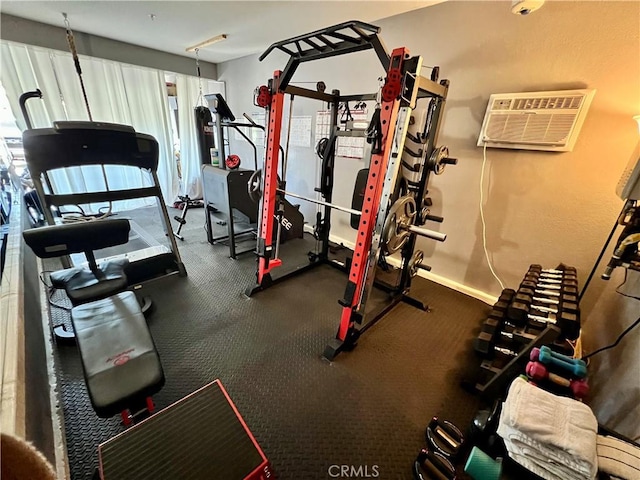 gym featuring baseboards and an AC wall unit