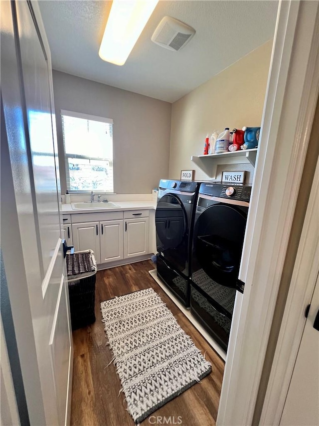 washroom featuring dark wood-type flooring, a sink, visible vents, independent washer and dryer, and cabinet space