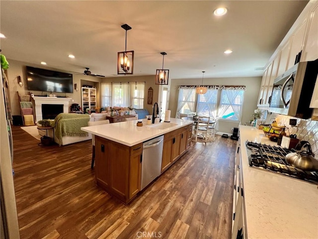 kitchen featuring dark wood-style flooring, a fireplace, a sink, light countertops, and appliances with stainless steel finishes