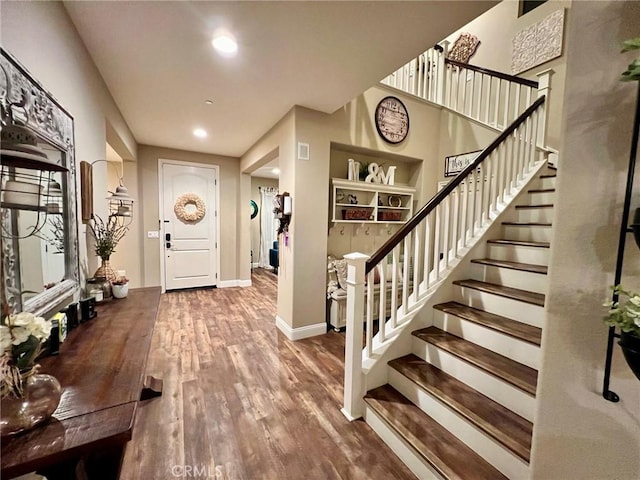 foyer entrance featuring baseboards, stairway, wood finished floors, and recessed lighting