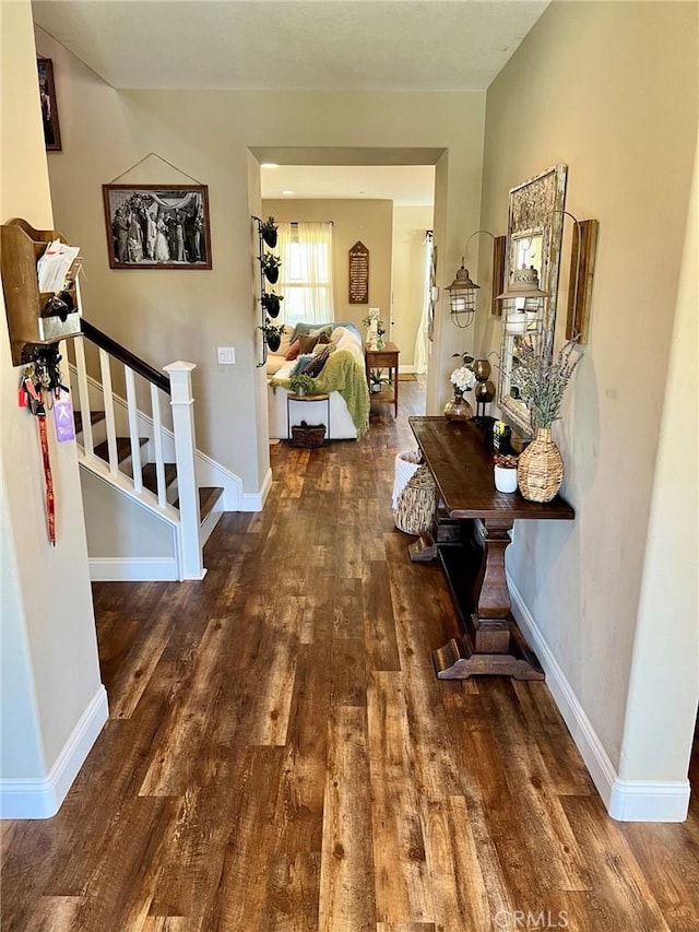 hall with stairs, baseboards, and wood finished floors