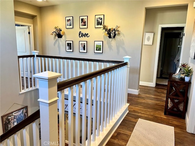 hall featuring baseboards, an upstairs landing, and wood finished floors