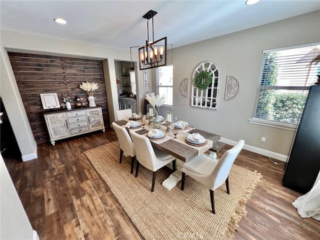 dining space with a healthy amount of sunlight, a notable chandelier, baseboards, and dark wood-type flooring