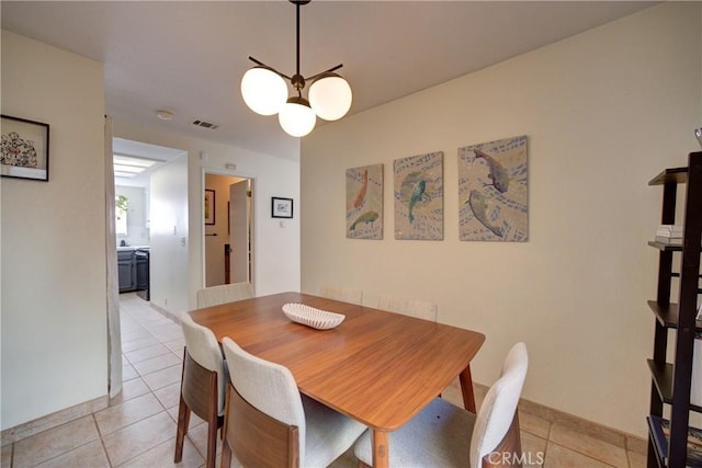 dining area featuring light tile patterned floors, baseboards, visible vents, and a chandelier