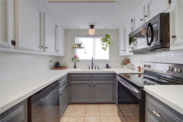 kitchen featuring range with electric stovetop, tasteful backsplash, gray cabinets, stainless steel dishwasher, and a sink