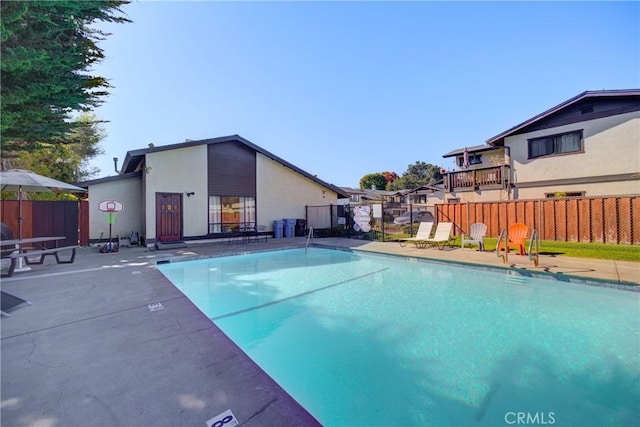 pool with a patio area and fence