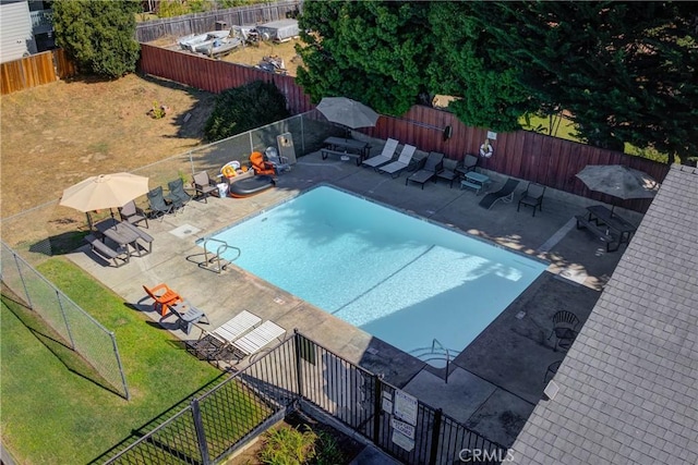 community pool with a patio area, a fenced backyard, and a lawn