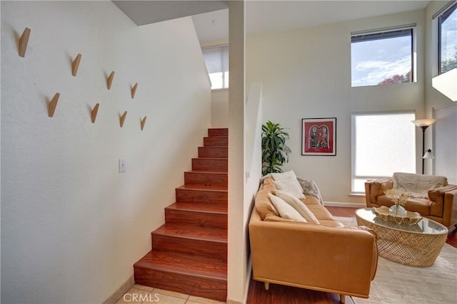 stairway featuring a high ceiling and baseboards