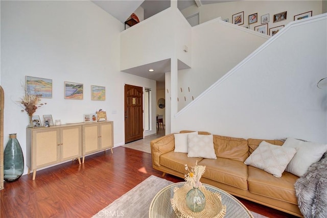 living room with stairs, wood finished floors, and a towering ceiling