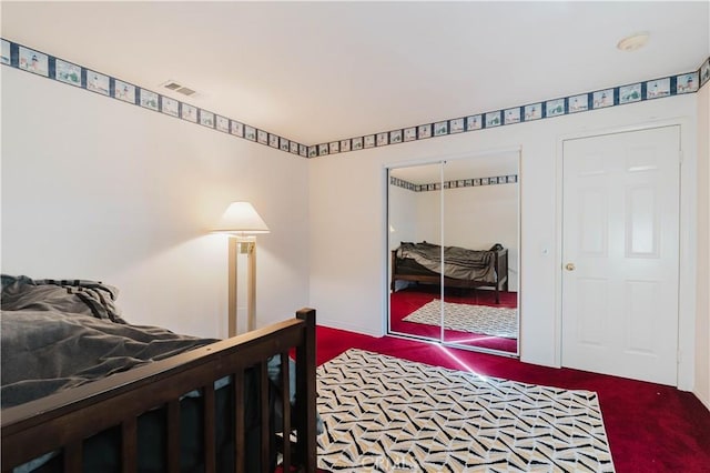 carpeted bedroom with visible vents and a closet