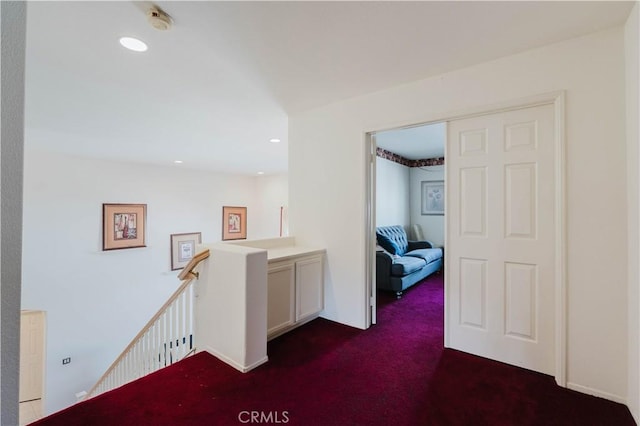 corridor featuring recessed lighting, dark carpet, and an upstairs landing