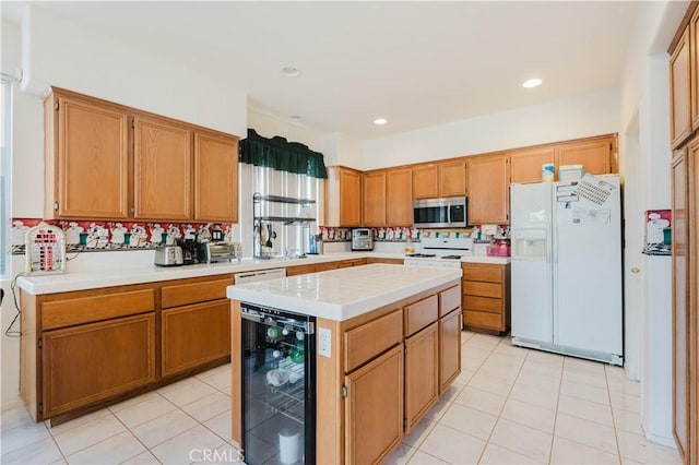 kitchen with light tile patterned floors, beverage cooler, white appliances, a kitchen island, and light countertops