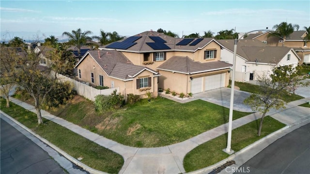 view of front of property featuring stucco siding, solar panels, concrete driveway, a front yard, and fence