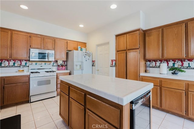 kitchen with tile countertops, white appliances, brown cabinetry, and recessed lighting