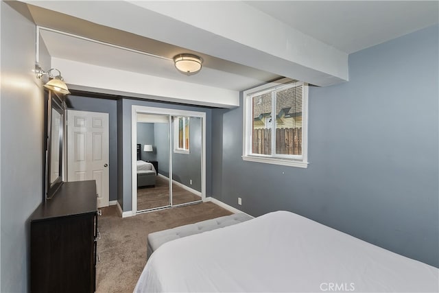 carpeted bedroom with a closet and baseboards