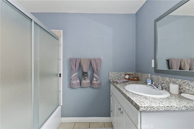 bathroom featuring baseboards, combined bath / shower with glass door, vanity, and tile patterned floors