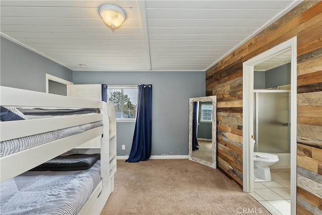 bedroom featuring carpet, connected bathroom, wooden walls, and baseboards