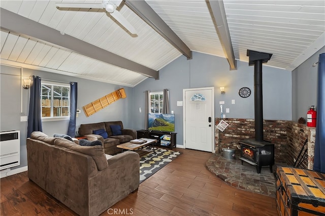 living room with ceiling fan, a wood stove, vaulted ceiling with beams, and wood finished floors