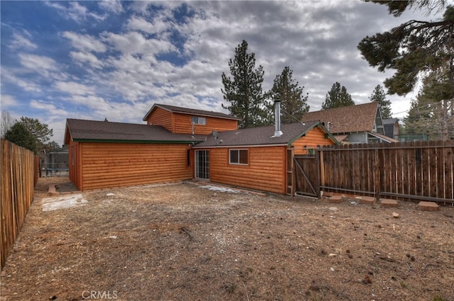 rear view of property featuring log veneer siding and fence