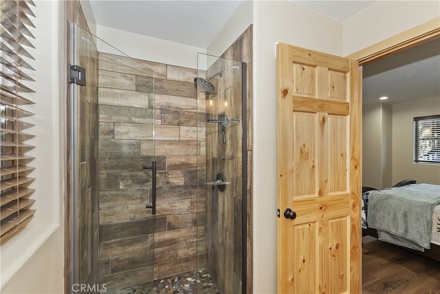 ensuite bathroom featuring a stall shower, ensuite bath, and wood finished floors