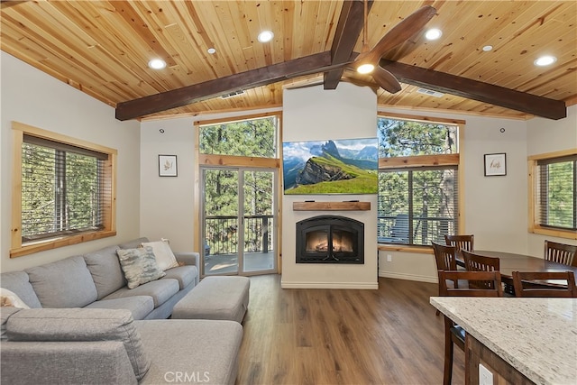 living area featuring vaulted ceiling with beams, a lit fireplace, and a wealth of natural light