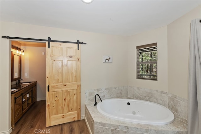 full bathroom featuring a tub with jets, wood finished floors, and vanity