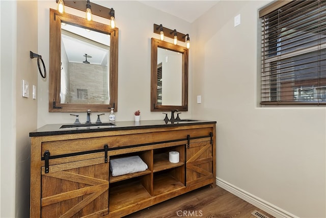 full bath with double vanity, baseboards, a sink, and wood finished floors