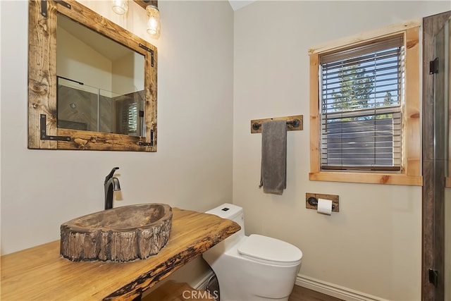 full bath with a sink, toilet, and an enclosed shower