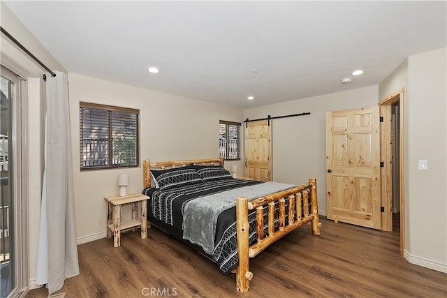 bedroom with baseboards, a barn door, dark wood-style flooring, and recessed lighting