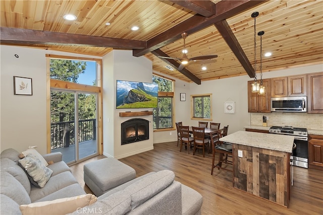 living area featuring dark wood-style floors, a warm lit fireplace, wooden ceiling, and vaulted ceiling with beams