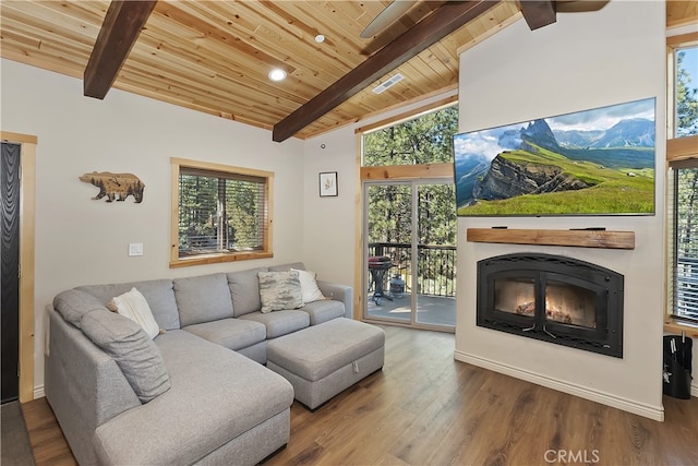 living area with vaulted ceiling with beams, a glass covered fireplace, wooden ceiling, and wood finished floors