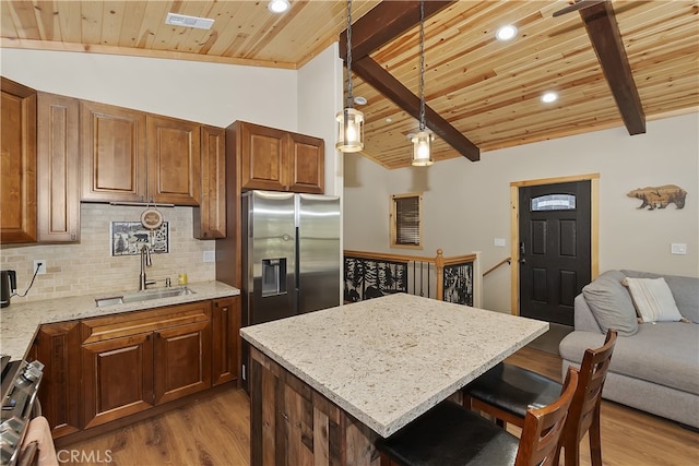 kitchen featuring lofted ceiling with beams, appliances with stainless steel finishes, wooden ceiling, and a sink