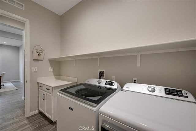 laundry area featuring cabinet space, visible vents, baseboards, dark wood-style flooring, and washing machine and dryer