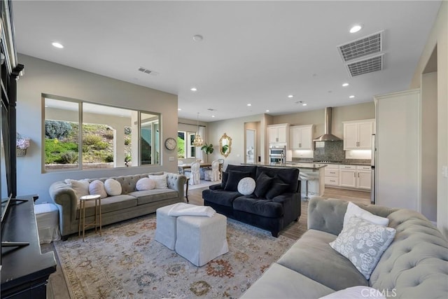 living room featuring light wood-type flooring, visible vents, and recessed lighting