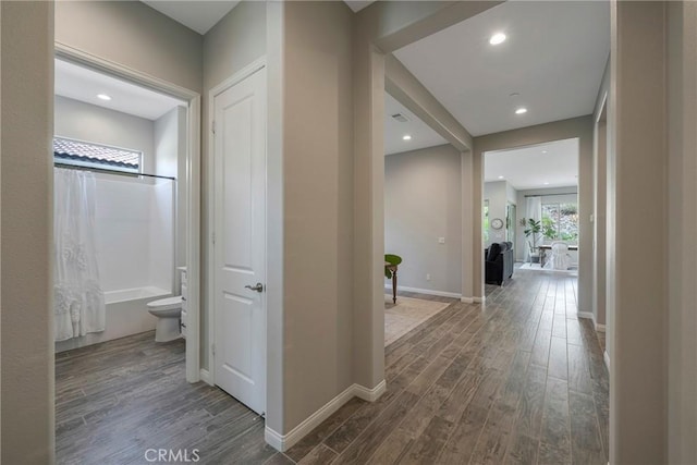 hallway with recessed lighting, visible vents, baseboards, and wood finished floors