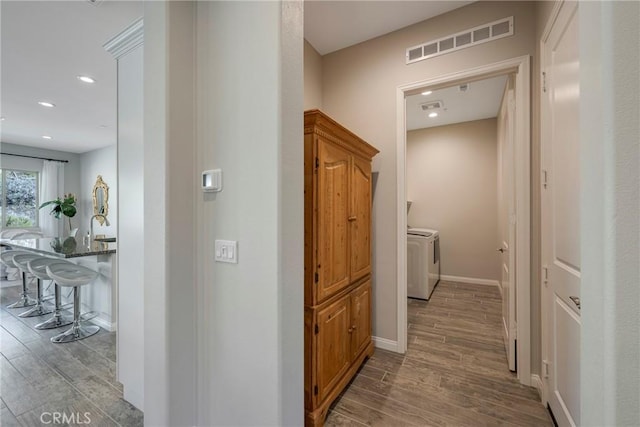 hallway with recessed lighting, visible vents, washing machine and dryer, wood finished floors, and baseboards