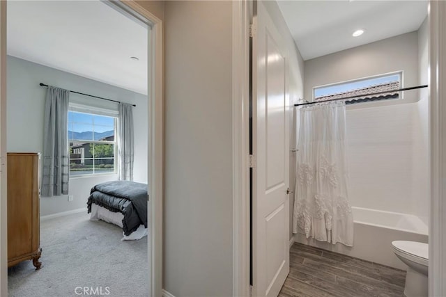 bathroom featuring shower / bath combo, baseboards, toilet, wood finished floors, and recessed lighting