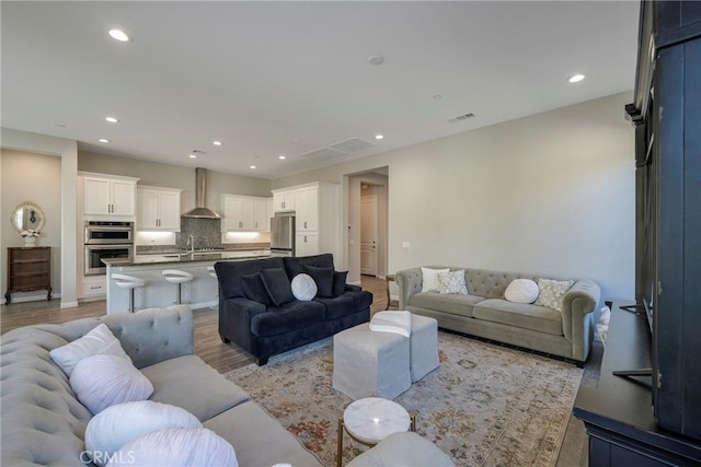 living room with light wood-type flooring, visible vents, and recessed lighting