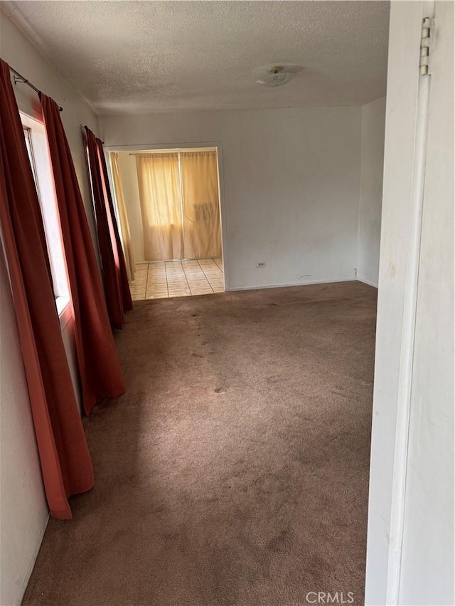 tiled empty room with carpet and a textured ceiling