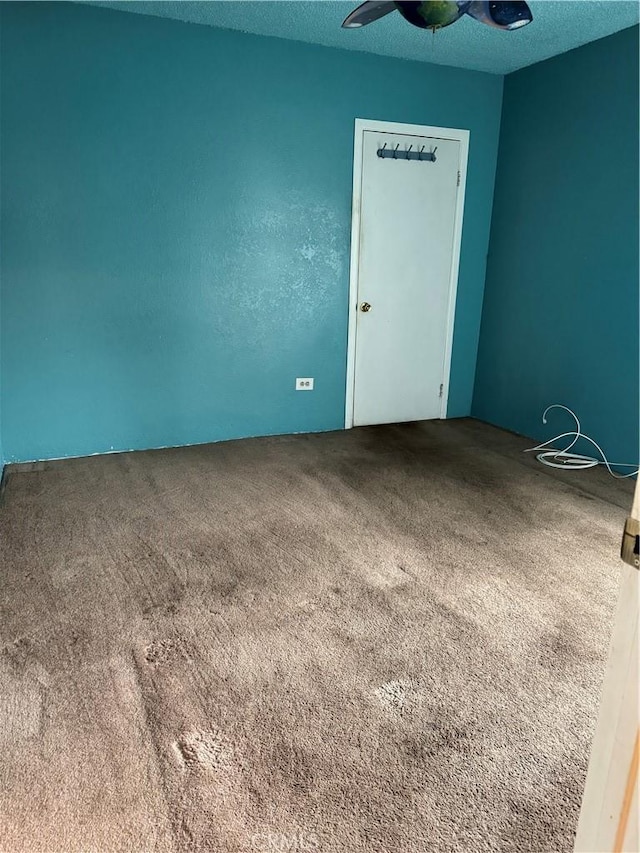 carpeted spare room featuring ceiling fan and a textured ceiling