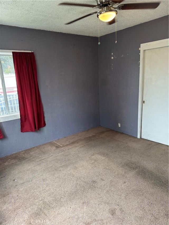 carpeted empty room with a textured ceiling and ceiling fan