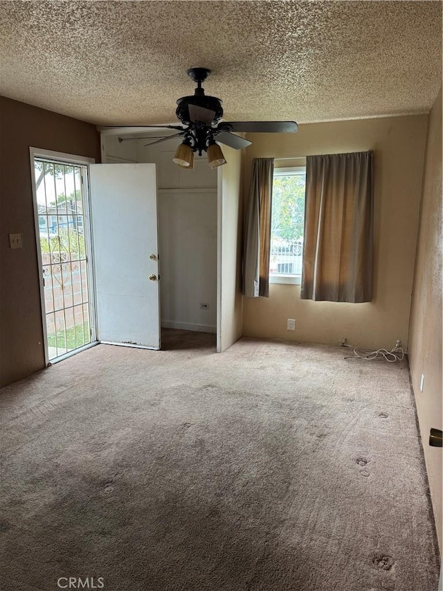 carpeted spare room with a healthy amount of sunlight, ceiling fan, and a textured ceiling