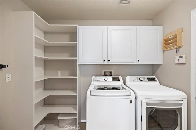 laundry area with visible vents, washing machine and dryer, and cabinet space