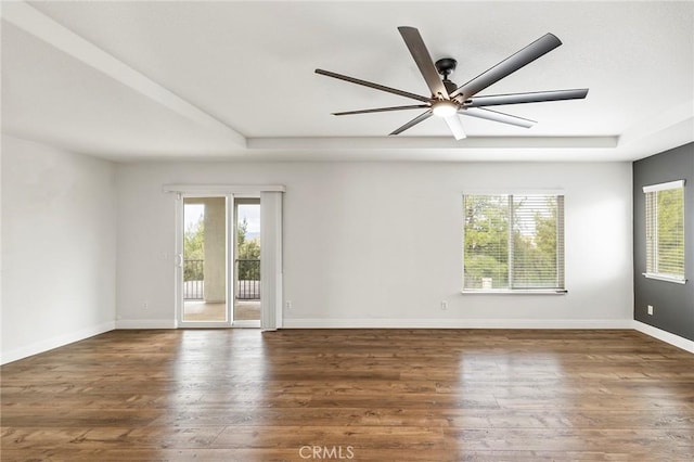 empty room featuring plenty of natural light, wood finished floors, and baseboards