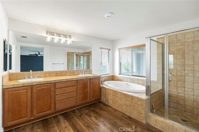 full bathroom featuring a bath, a stall shower, a sink, and wood finished floors