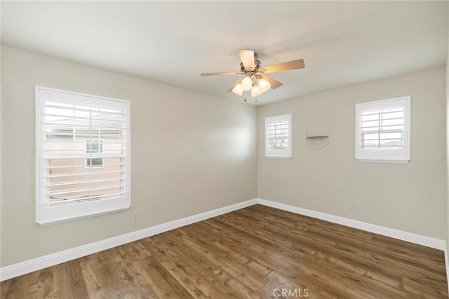 empty room featuring ceiling fan, baseboards, and wood finished floors