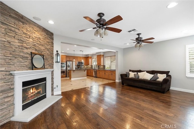 unfurnished living room featuring light wood finished floors, recessed lighting, visible vents, a glass covered fireplace, and baseboards