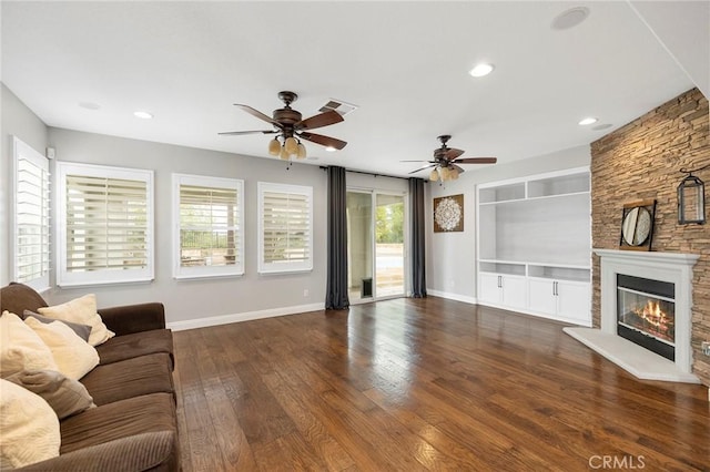 unfurnished living room featuring a stone fireplace, visible vents, baseboards, built in features, and hardwood / wood-style floors