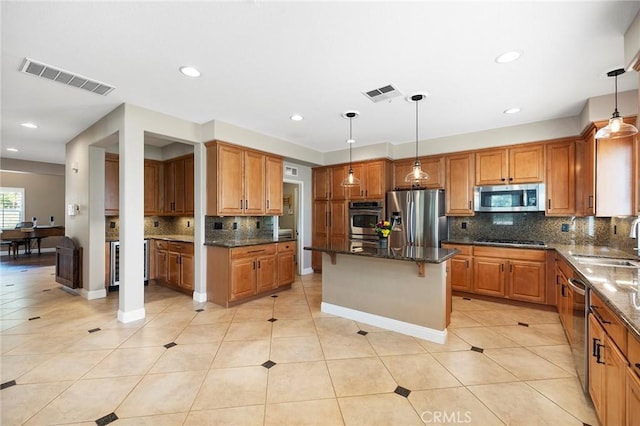 kitchen featuring appliances with stainless steel finishes, visible vents, a sink, and dark stone countertops